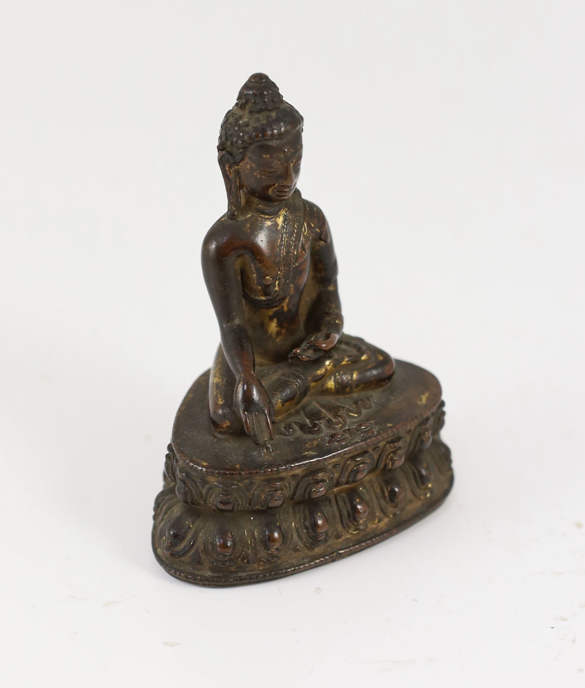 A small Tibetan gilt copper alloy seated figure of Buddha Shakyamuni, probably 15th/16th century, 10.4cm